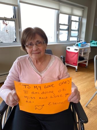 Resident holding a sign for her family during COVID-19