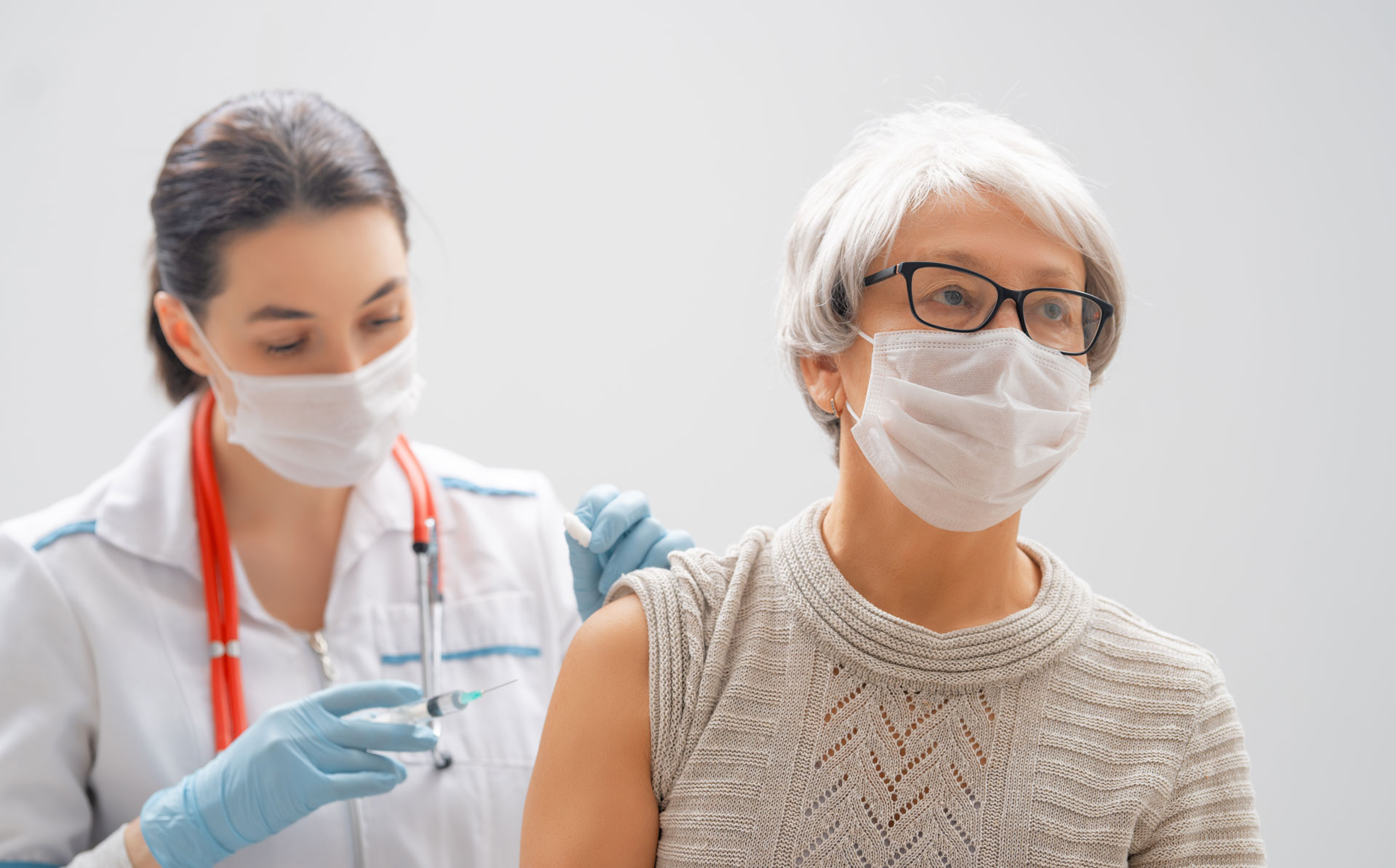 nurse administering COVID-19 vaccine to senior female