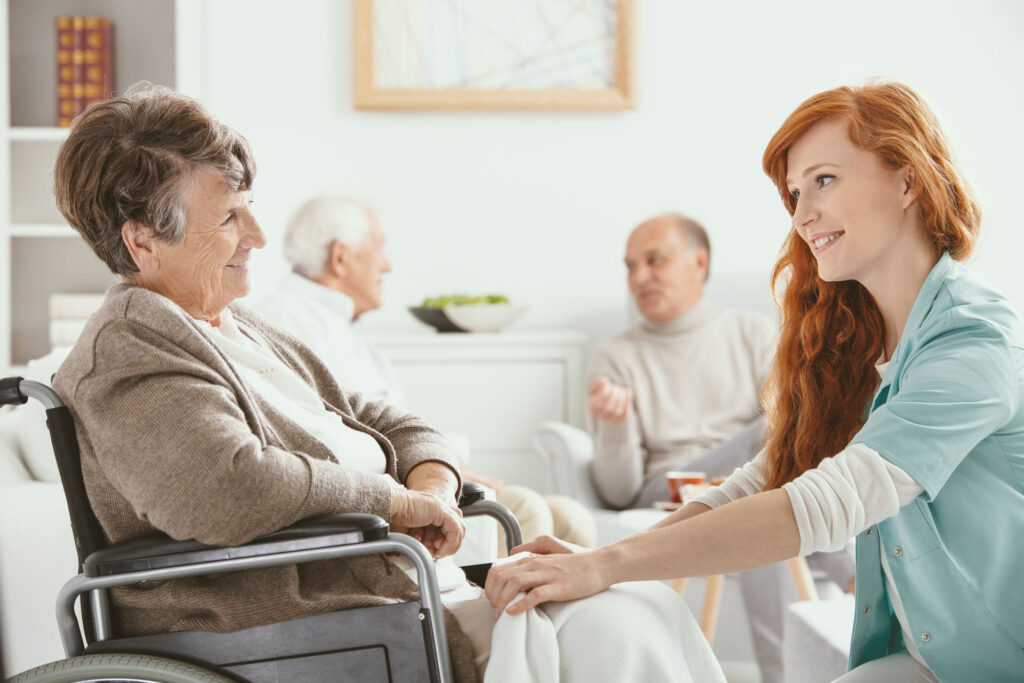 nurse helping senior woman in wheelchair inside a nursing home