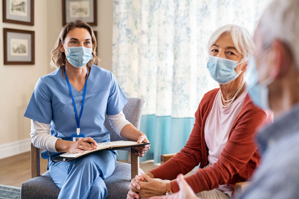 nurse speaking with senior couple wearing protective face masks