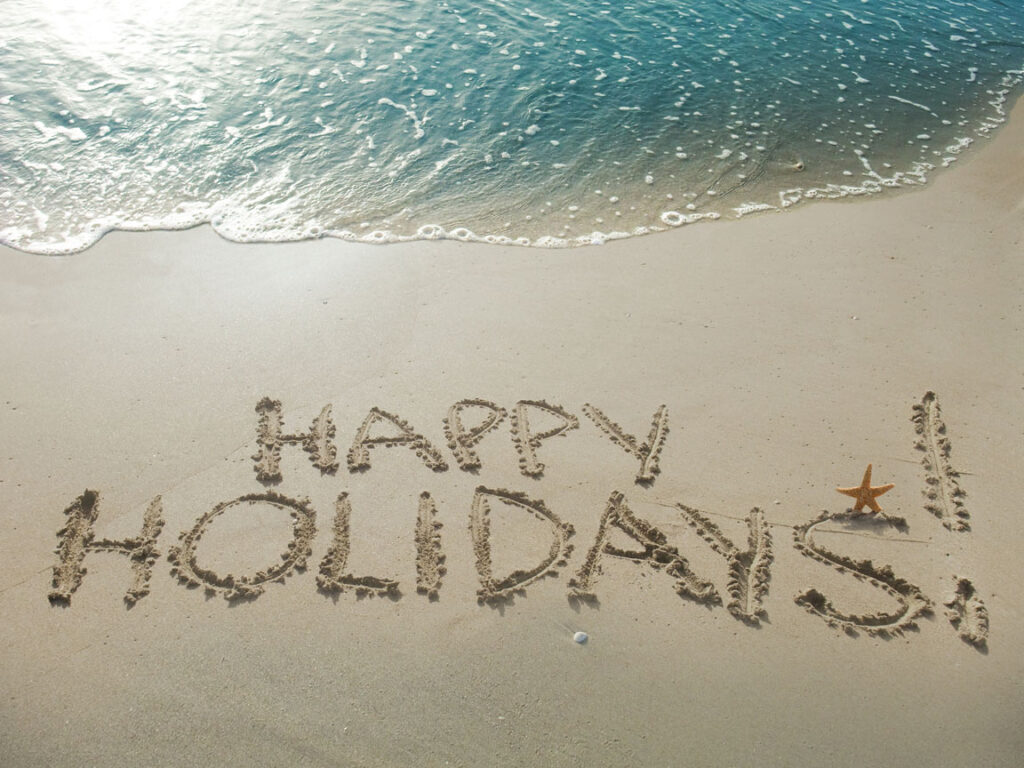 Happy holidays written in the sand