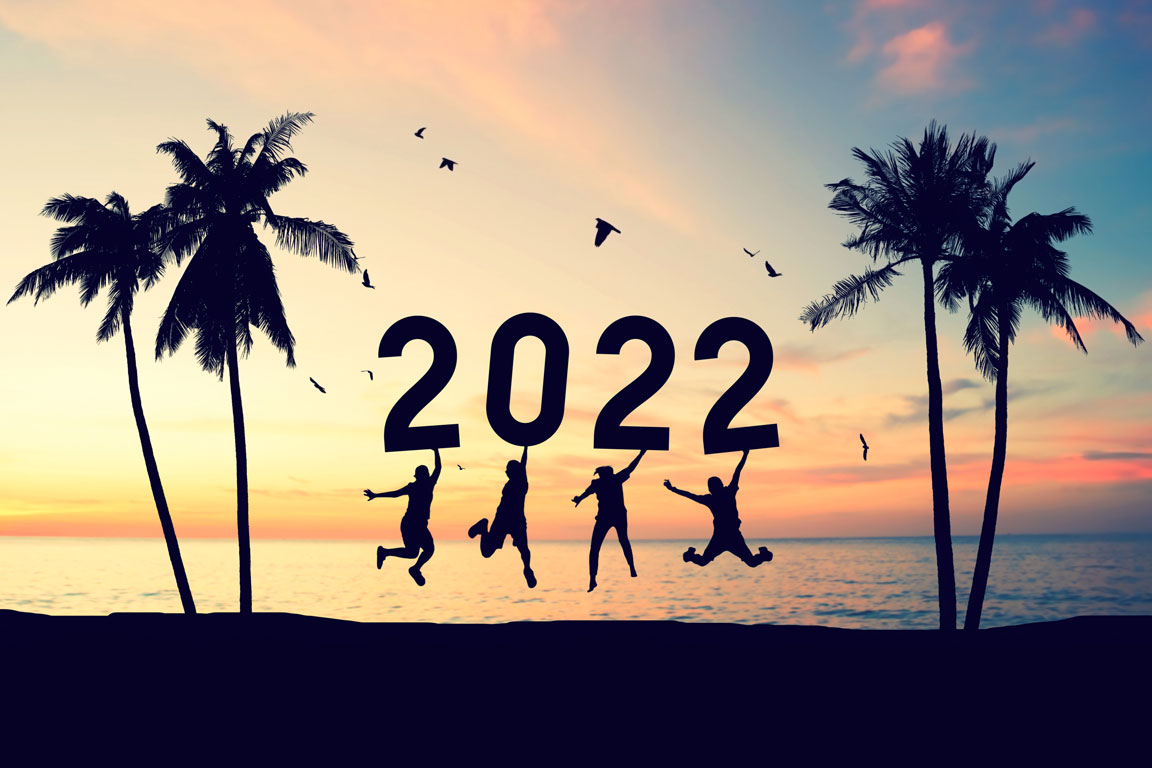 silhouettes holding up 2022 at a beach during the sunset