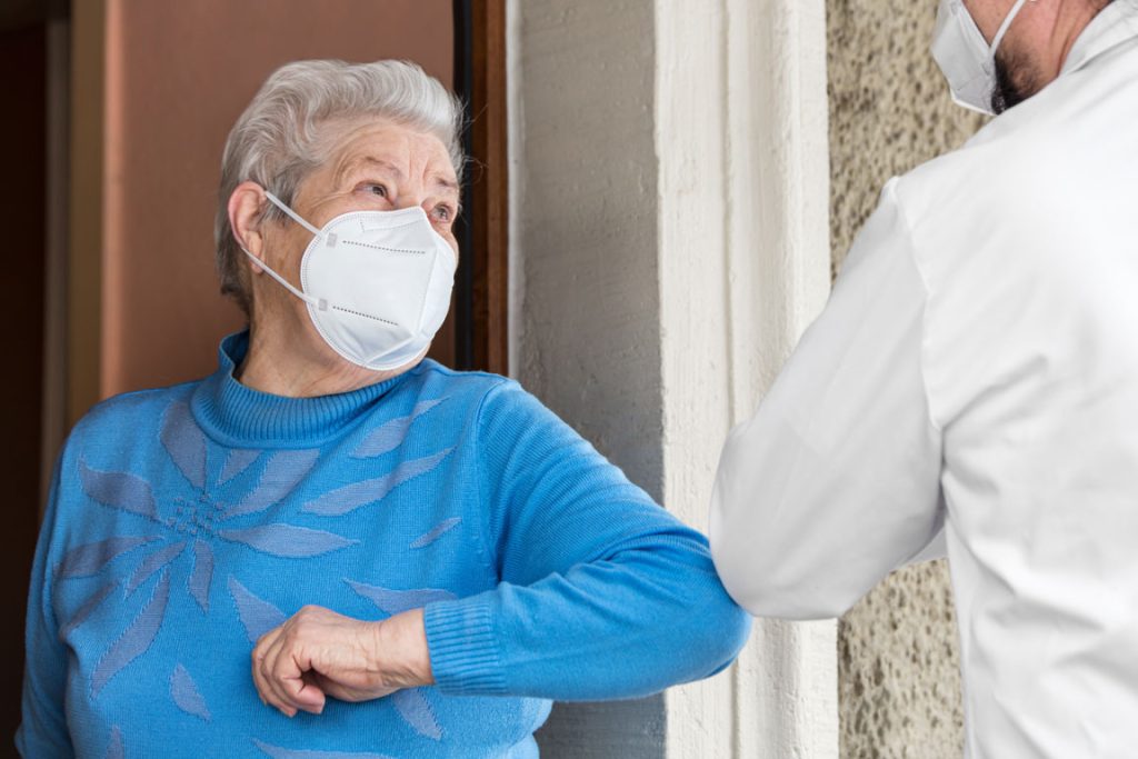 senior female and doctor wearing protective face masks