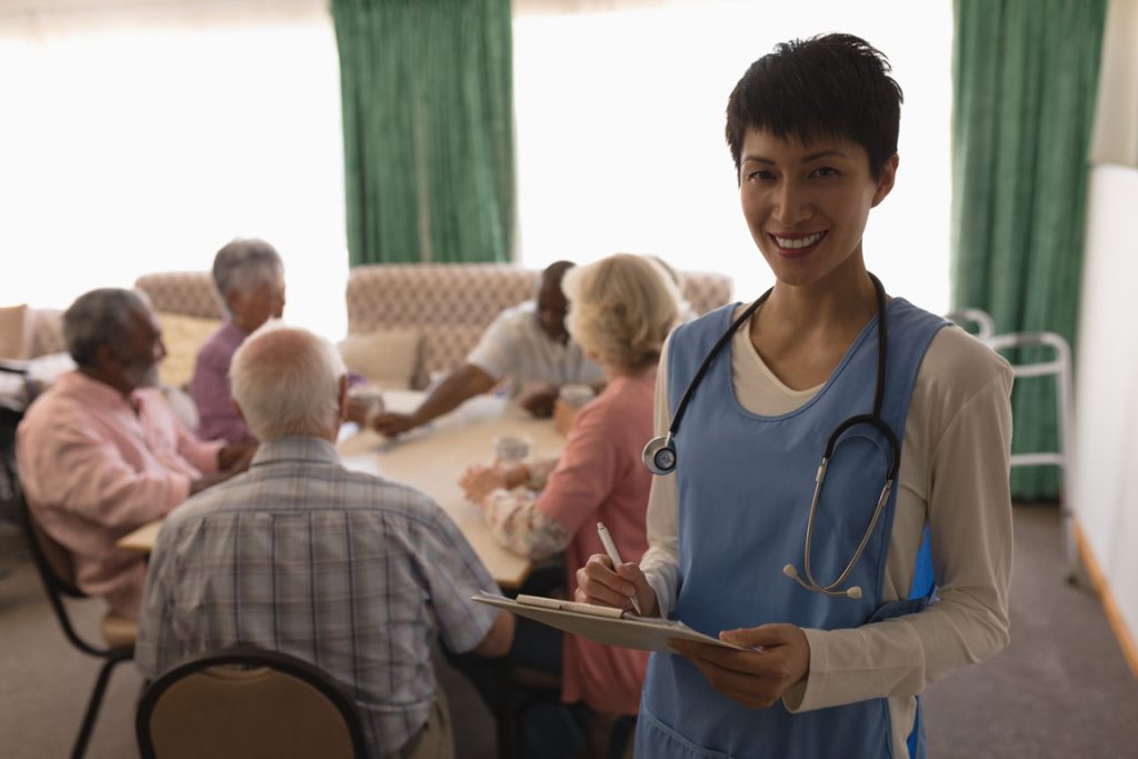 female nurse holding clipboard in front of seniors at a nursing home