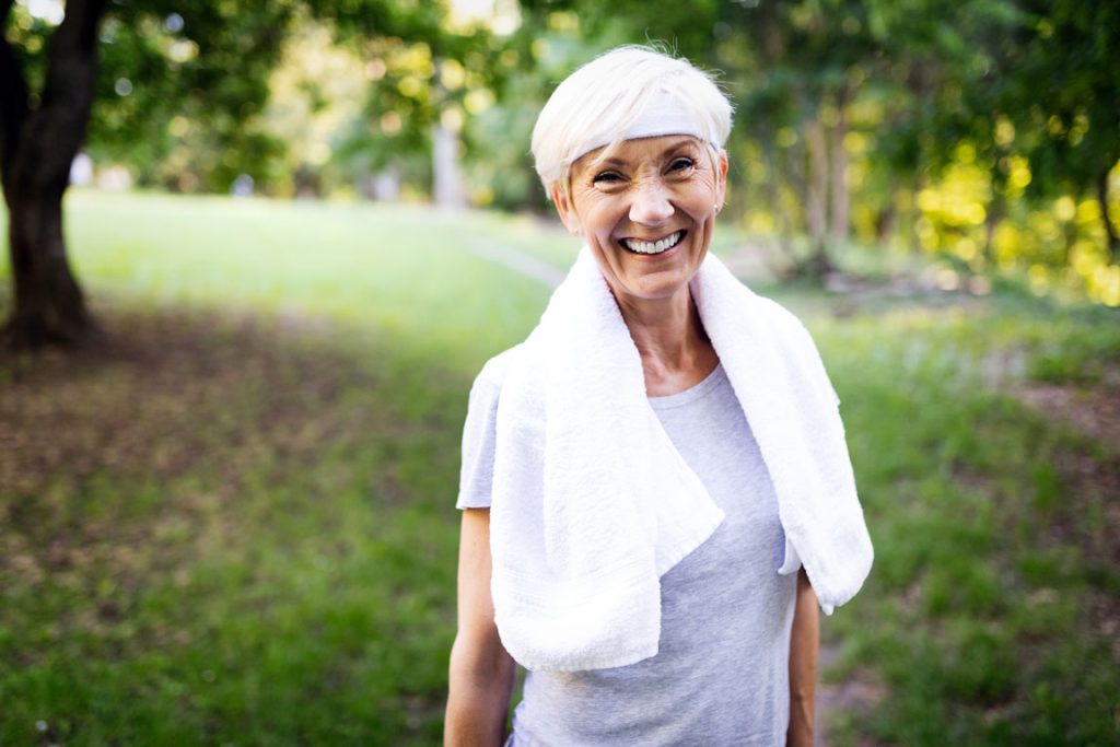 senior woman outside with a towel around her neck after a workout