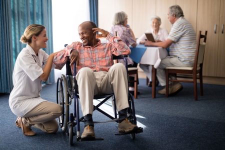 nurse attending African American male resident in a wheelchair at nursing home
