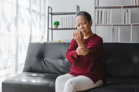senior Asian female holding her wrist from arthritis